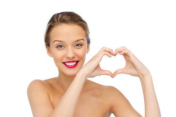 Image showing smiling young woman showing heart shape hand sign