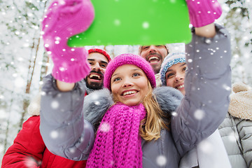 Image showing smiling friends with tablet pc in winter forest