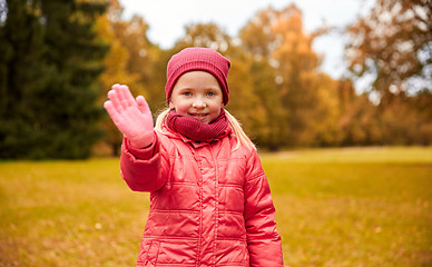 Image showing happy little girl waving hand in autumn park