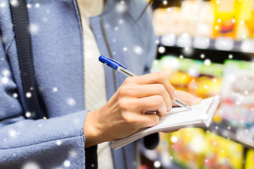 Image showing close up of woman writing to notepad in grocery