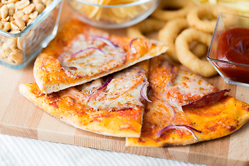 Image showing close up of pizza and other snacks on wooden table