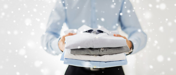 Image showing close up of businessman holding folded shirts