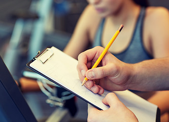 Image showing close up of trainer hands with clipboard in gym