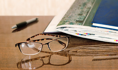 Image showing Glasses and Newspapers on the table surface.