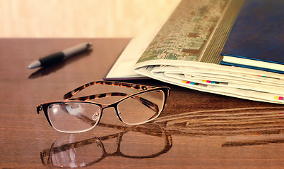 Image showing Glasses and Newspapers on the table surface.