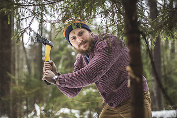 Image showing Young man is cutting christmas tree in the wood