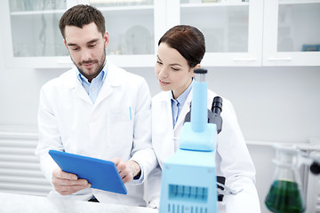 Image showing scientists with tablet pc and microscope in lab