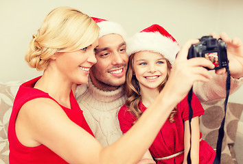 Image showing smiling family in santa helper hats taking picture