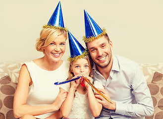 Image showing smiling family in blue hats blowing favor horns