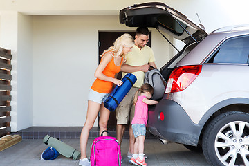 Image showing happy family packing things to car at home parking