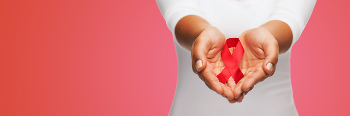 Image showing close up of hands with red AIDS awareness ribbon