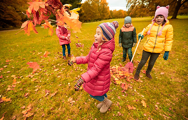 Image showing happy children playing with autumn leaves in park