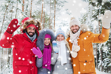 Image showing group of friends waving hands in winter forest