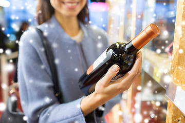 Image showing happy woman choosing and buying wine in market