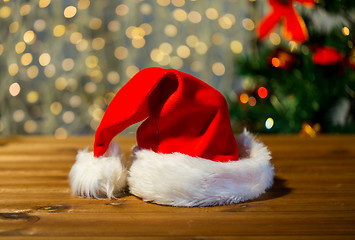 Image showing close up of santa hat on wooden table over lights