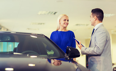 Image showing happy woman with car dealer in auto show or salon