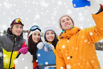 Image showing happy friends with snowboards and smartphone