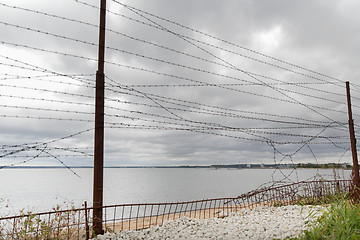 Image showing barb wire fence over gray sky and sea