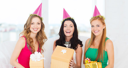 Image showing three smiling women in pink hats with gift boxes