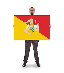 Image showing Smiling businessman holding a big card, flag of Sicily