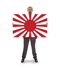 Image showing Smiling businessman holding a big card, flag of Japan