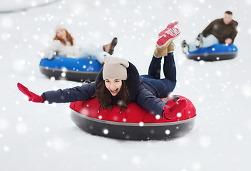 Image showing group of happy friends sliding down on snow tubes