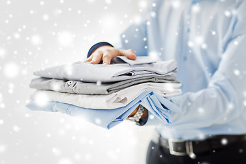 Image showing close up of businessman holding folded shirts