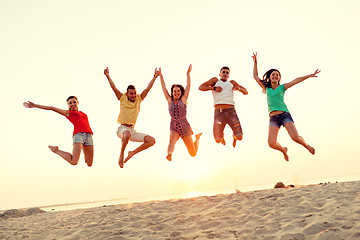 Image showing smiling friends dancing and jumping on beach