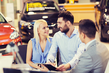 Image showing happy couple with car dealer in auto show or salon