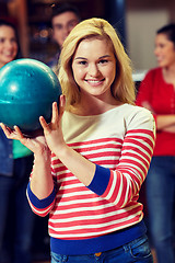 Image showing happy young woman holding ball in bowling club