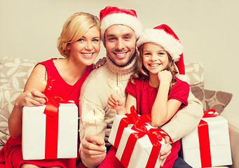 Image showing smiling family holding gift boxes and sparkles