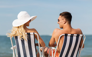 Image showing happy couple sunbathing in chairs on summer beach