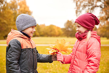 Image showing little boy giving autumn maple leaves to girl