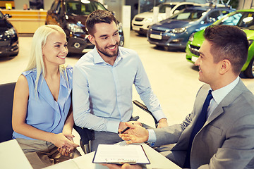 Image showing happy couple with car dealer in auto show or salon