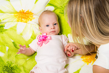 Image showing The two-month baby lying on the bed, sitting next to mom