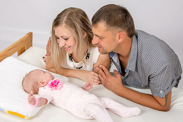 Image showing Mom and Dad with a smile, looking at her two month baby