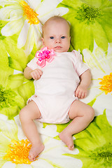 Image showing The two-month baby lying on the bed on his back looking at the frame