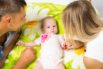 Image showing Mom and dad are looking at a two-month baby who is lying on the bed