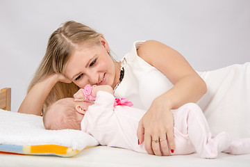 Image showing Mom lovingly watching her baby lying on the bed with him