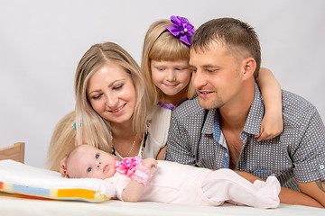 Image showing Mother, father and daughter, five-year look at newborn baby