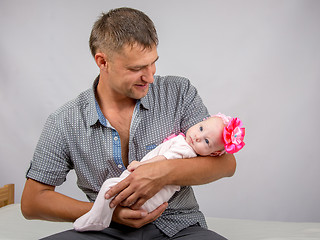 Image showing Joyful father holding newborn daughter and looks at her