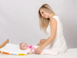 Image showing Happy mother sitting on a bed and looking at a two-month daughter