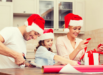 Image showing smiling family in santa helper hats with gift box