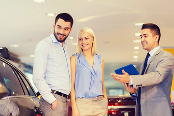 Image showing happy couple with car dealer in auto show or salon