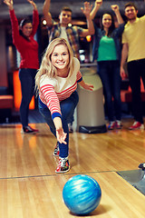 Image showing happy young woman throwing ball in bowling club