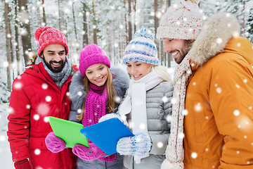 Image showing smiling friends with tablet pc in winter forest