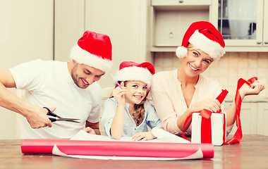 Image showing smiling family in santa helper hats with gift box