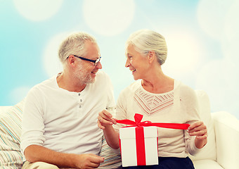 Image showing happy senior couple with gift box at home