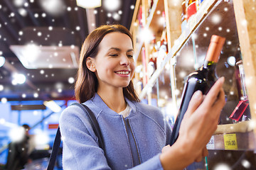 Image showing happy woman choosing and buying wine in market