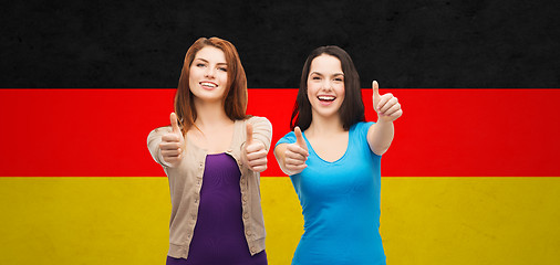 Image showing smiling girls showing thumbs up over german flag